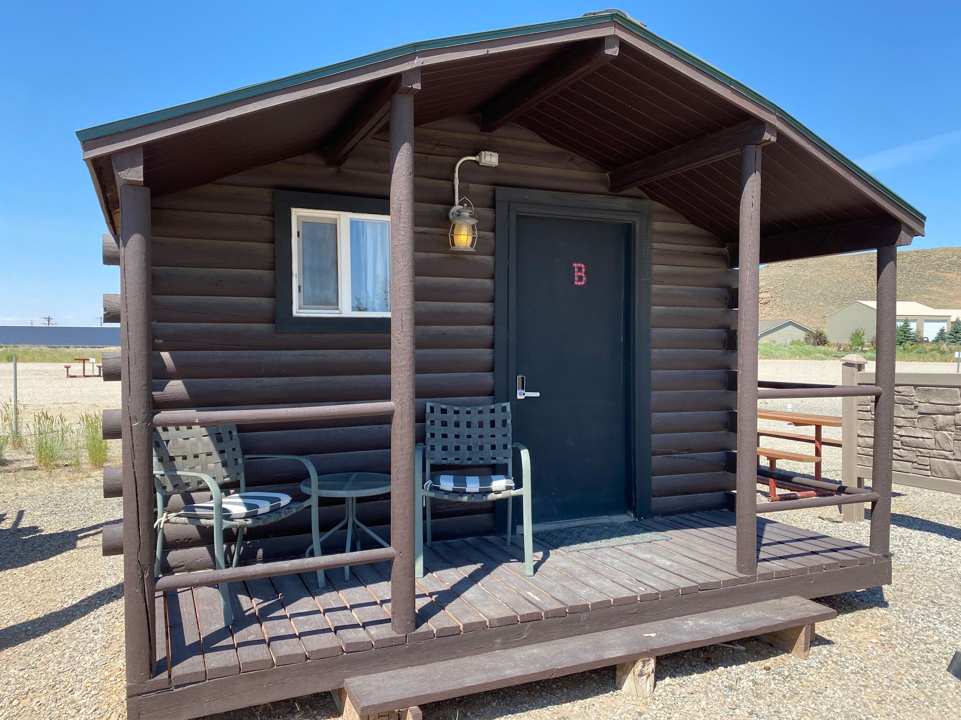A log cabin with a porch in the middle of a forest.