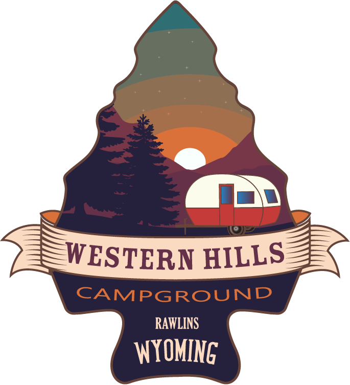 Logo for Western Hills Campground in Rawlins, Wyoming, featuring a sunset, pine trees, and a vintage camper in an arrowhead.