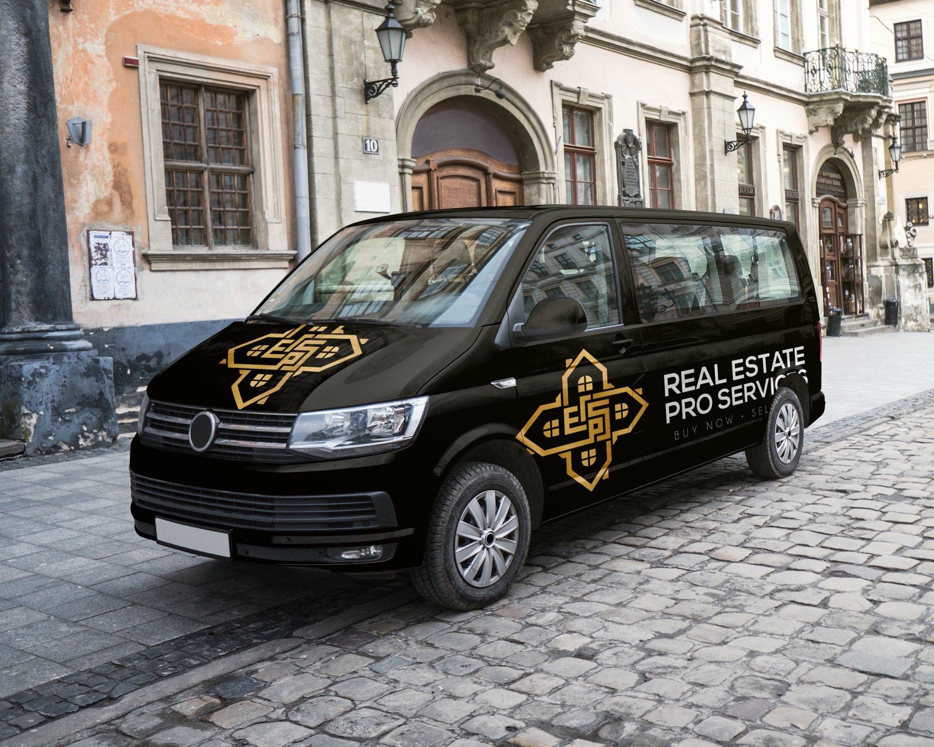 A black van is parked on a cobblestone street in front of a building.