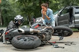 A woman in shock stands near a fallen motorbike and injured rider after a road crash, highlighting the urgent need for motorcycle accident lawyers.