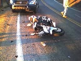 Aftermath of a high-impact motorcycle crash on a rural road, with debris scattered-illustrating the types of claims managed by motorcycle accident lawyers.