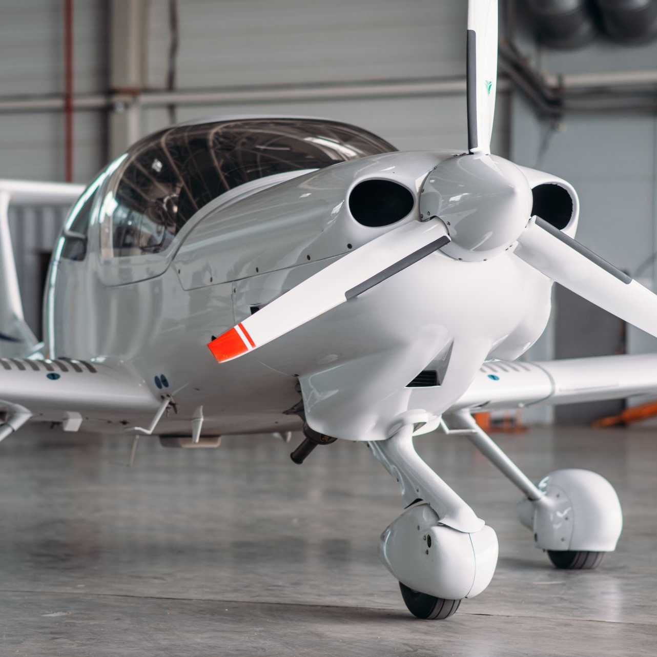 White single-engine airplane parked in a hangar.