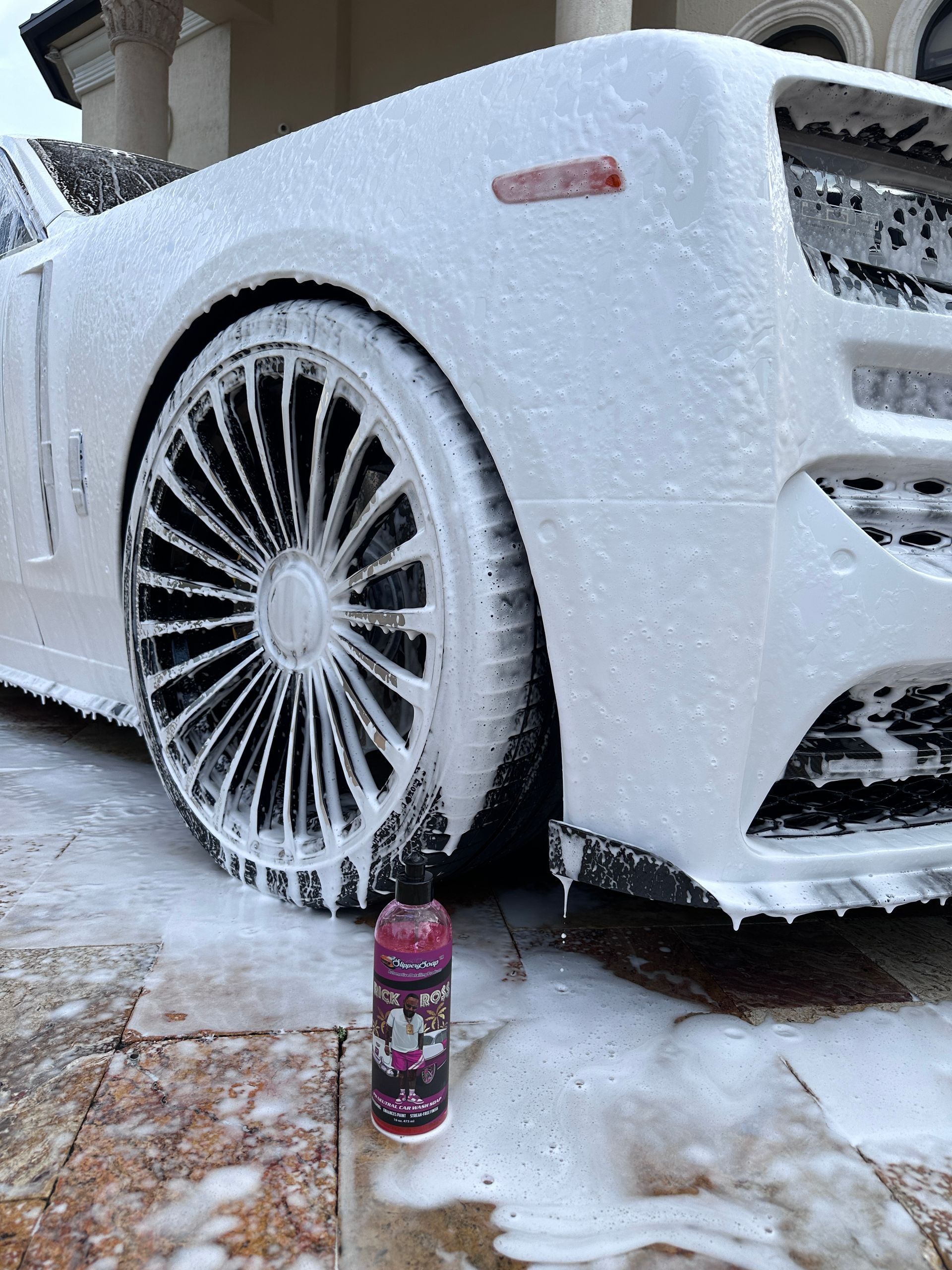 White car covered in foam suds, car wash in progress.