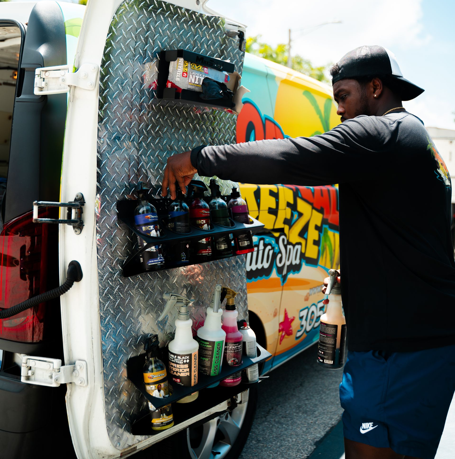 Person selecting a product from a car detailing service van. The van has detailing products attached to the open door.