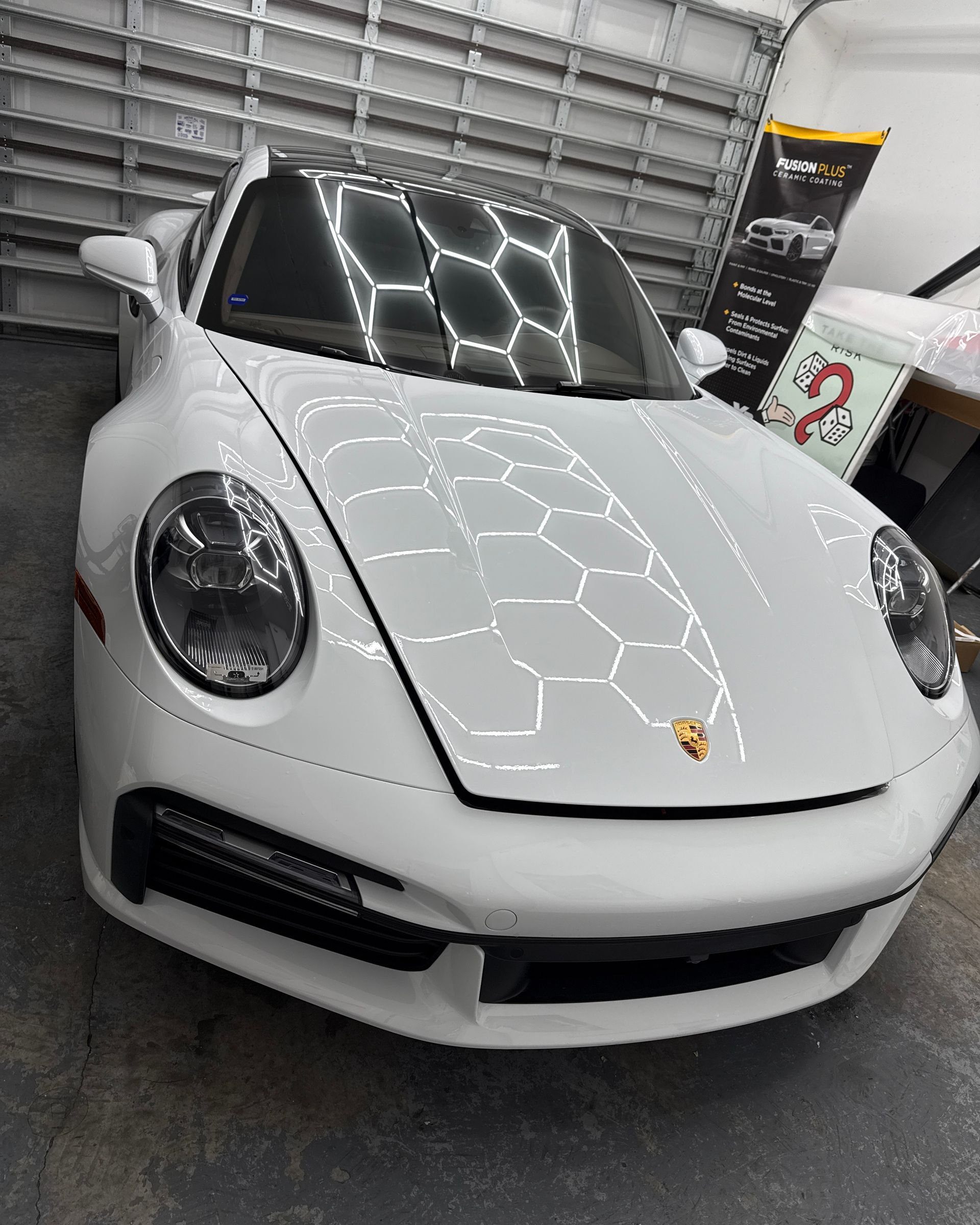 White Porsche 911 in a garage, reflecting the overhead lights.