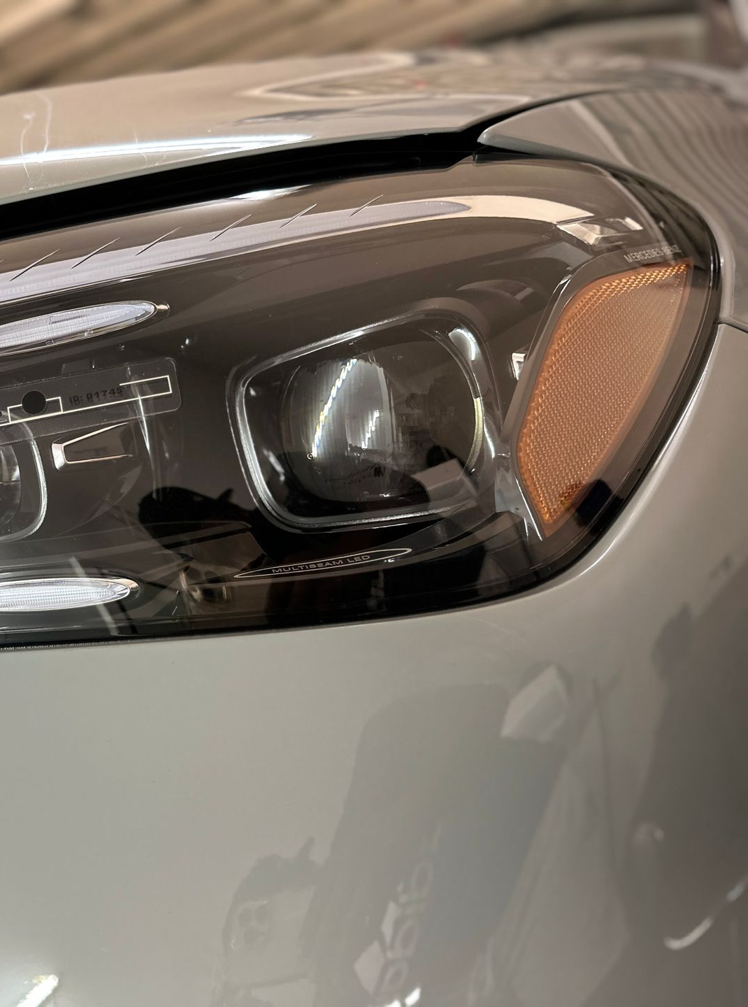 Close-up of a car's headlight. Black housing with amber reflector. Silver body panel.