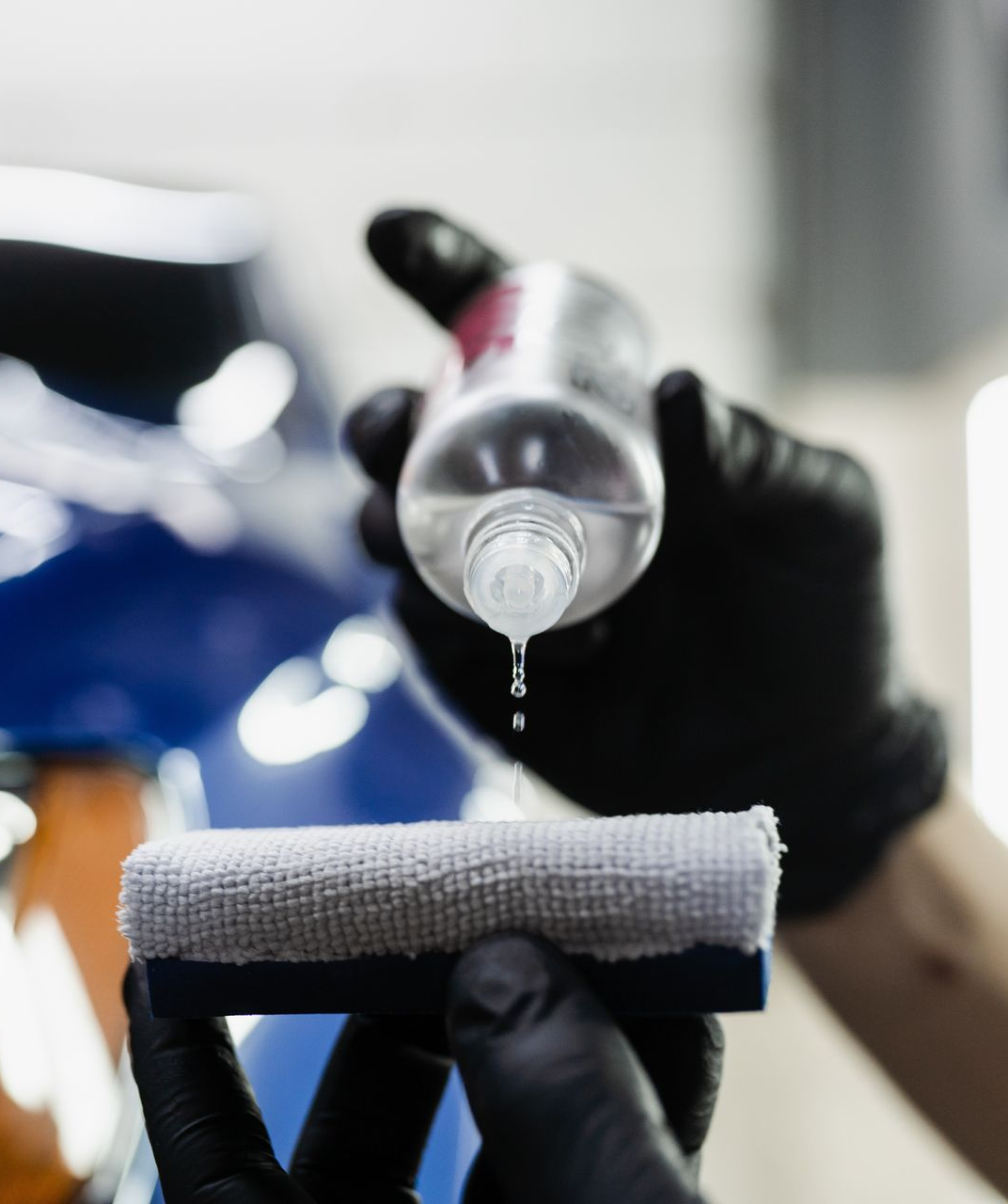 Close-up of clear water droplets on a smooth, reflective, blue surface.