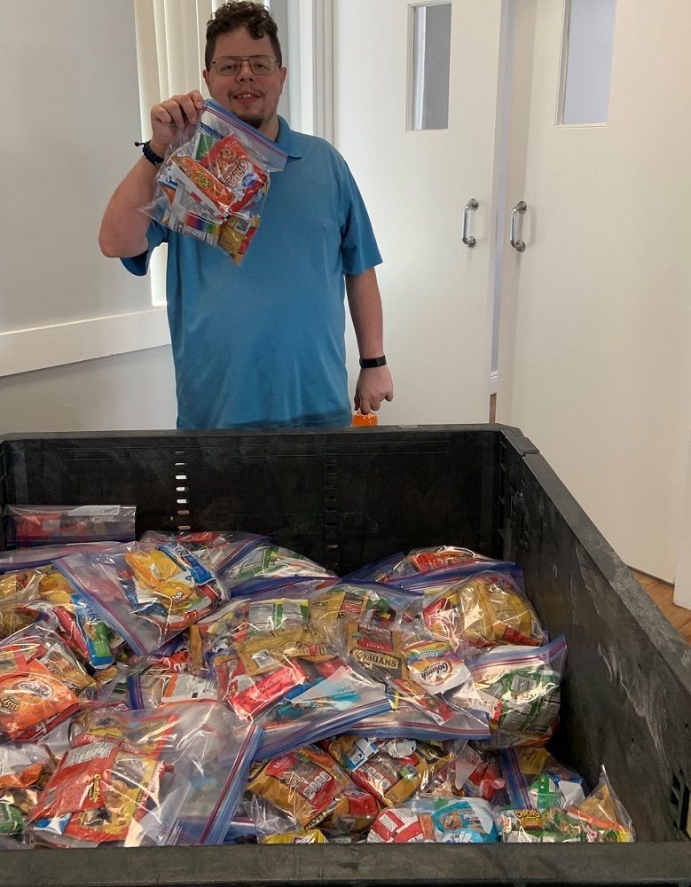 You man holding up snack packs for distribution.