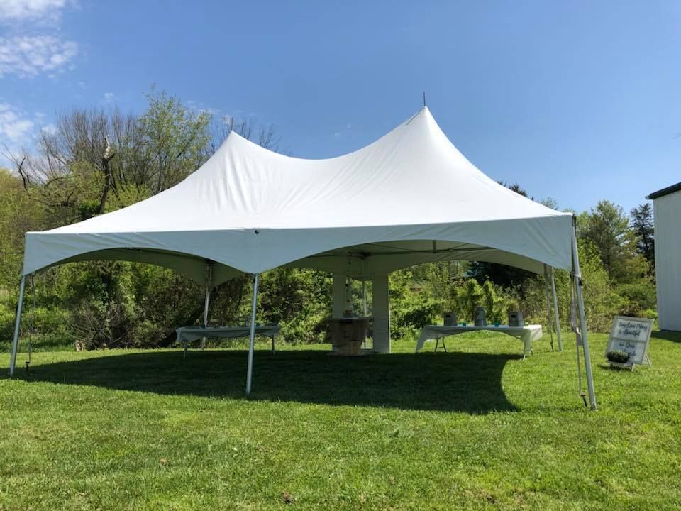 A white tent is sitting in the middle of a grassy field.