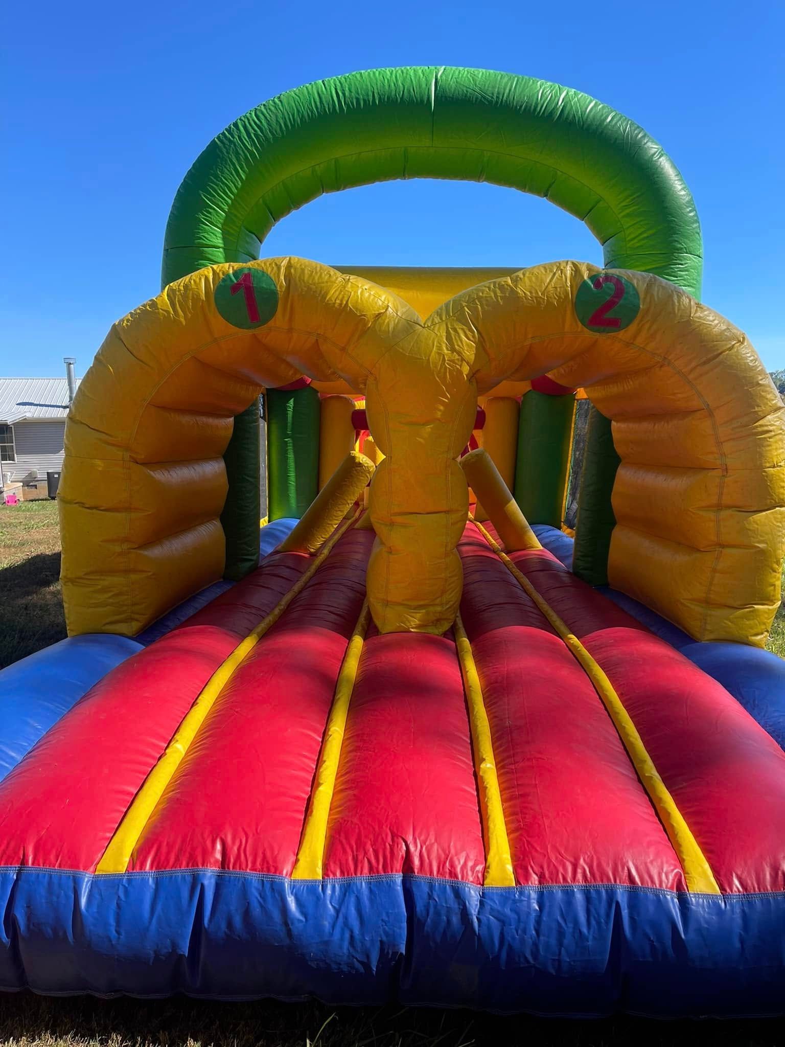 A large colorful bouncy house is sitting on top of a lush green field.