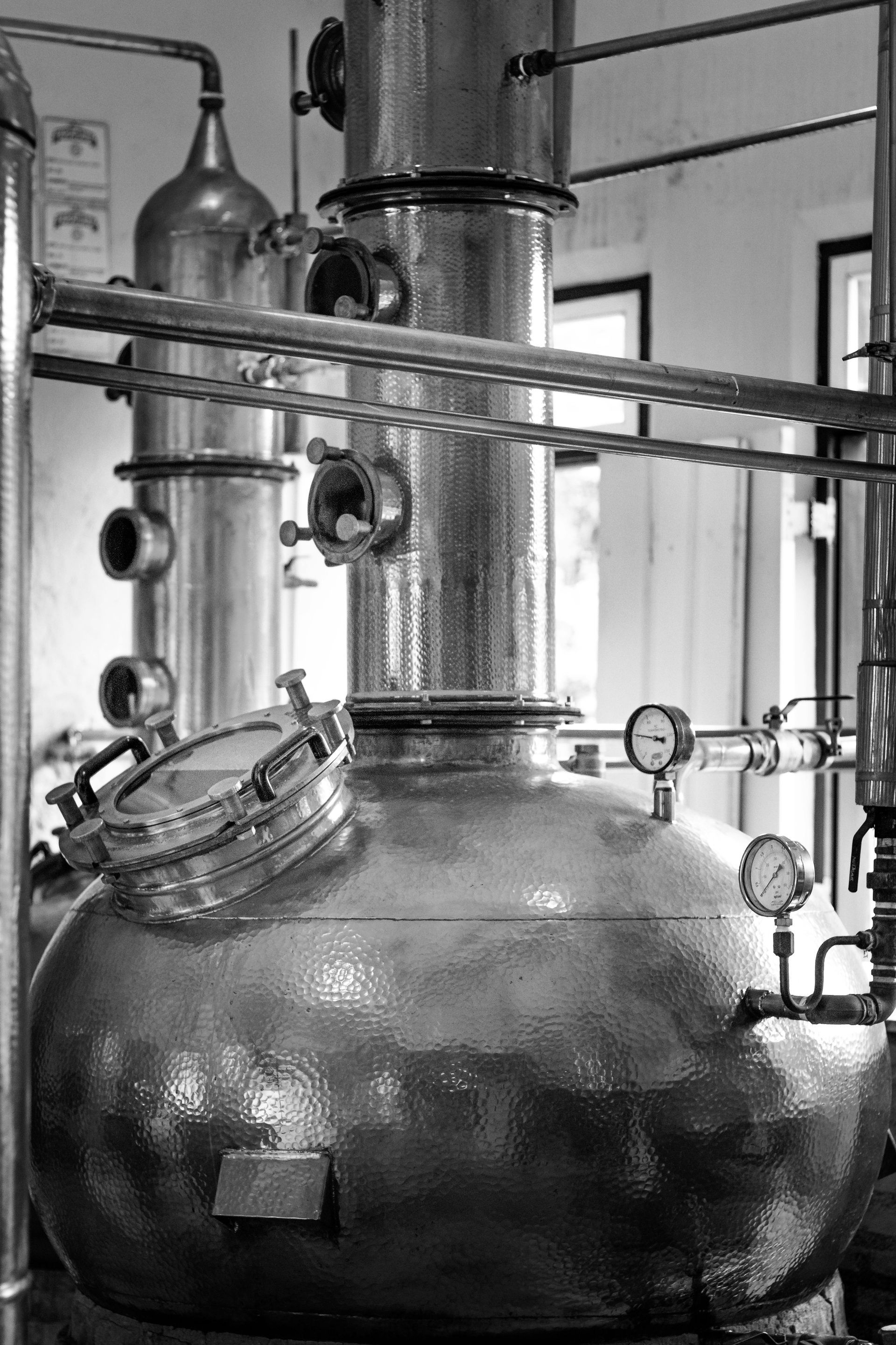 A black and white photo of a large metal tank in a factory.