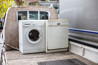 Front-loading washer and dishwasher on a flatbed truck, ready for transport