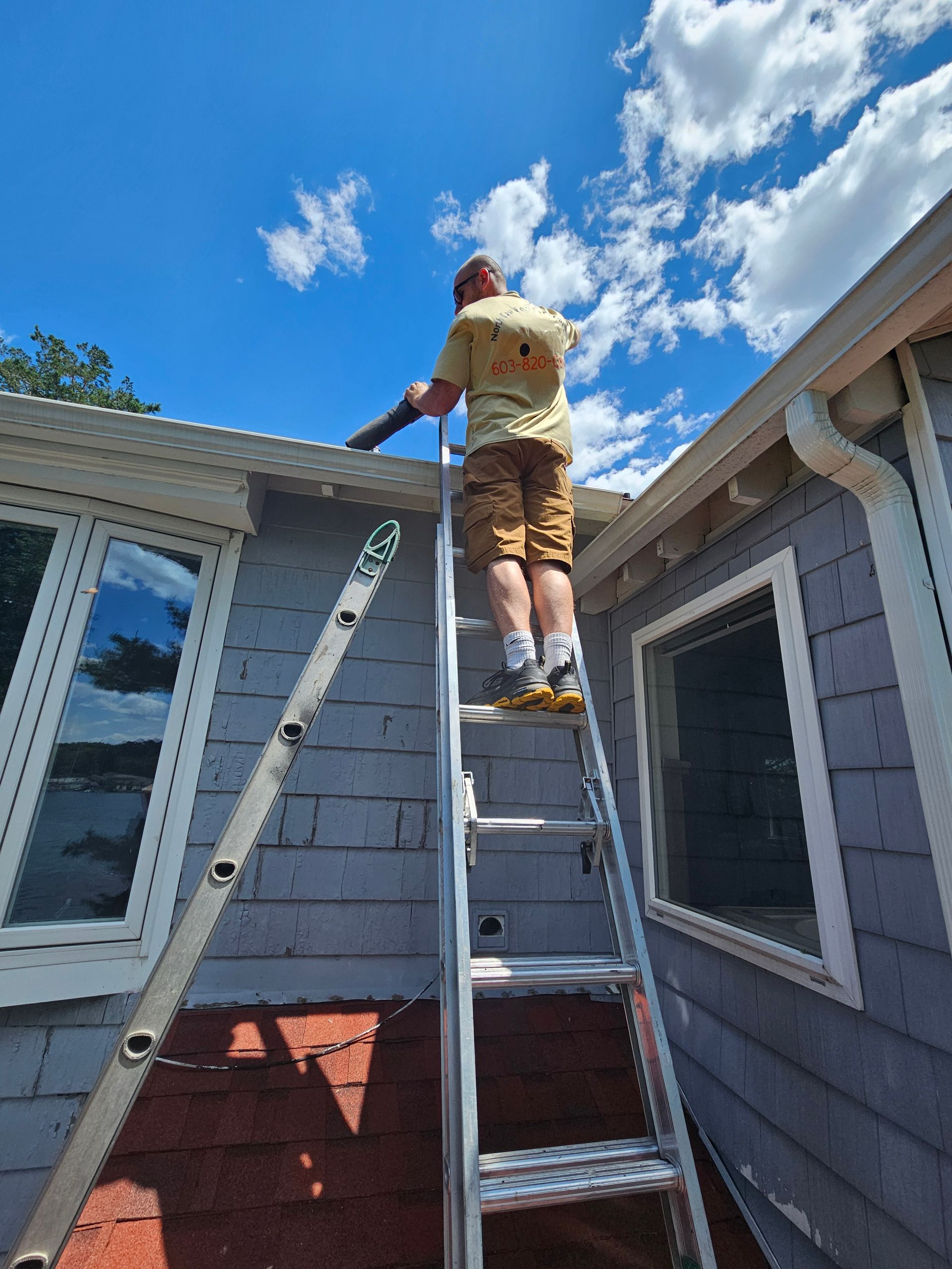 Cleaning gutters on a two story home with a leaf blower. Using a leaf blower to clean leaves out of gutters.
