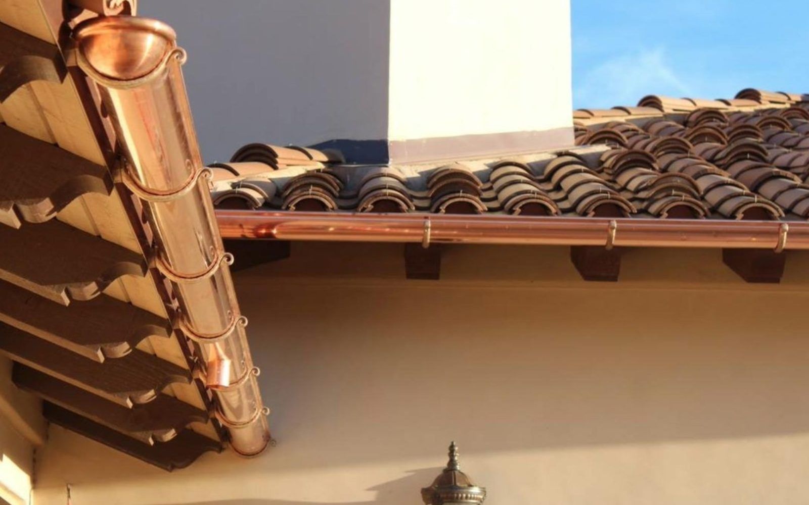 A man is standing on a ladder on the side of a brick building.