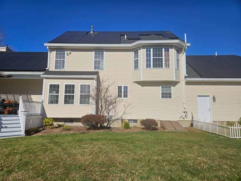 The back of a house with a large lawn in front of it.