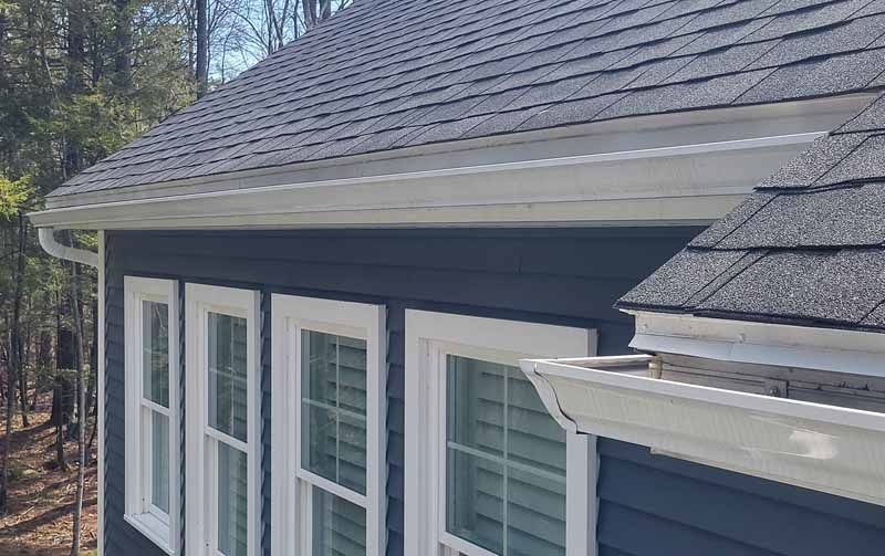 A blue house with white windows and a gray roof.