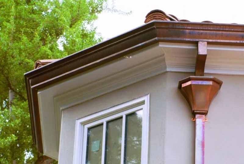 A house with a copper gutter on the side of it and a window.