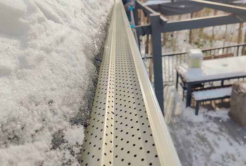 A gutter with snow on it and a table in the background.
