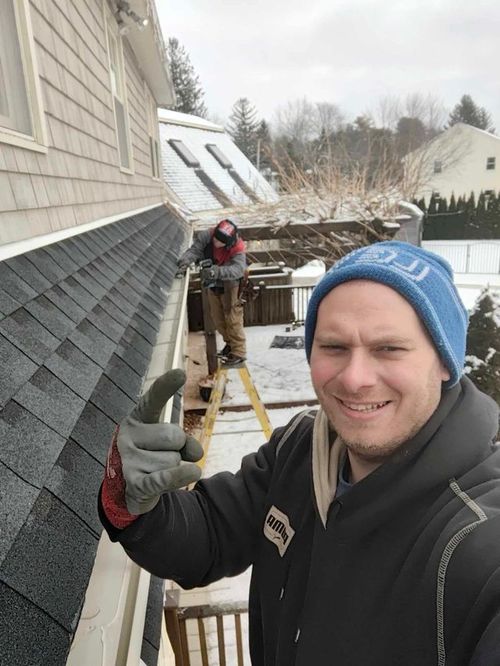 A man wearing a blue hat is standing in front of a house.