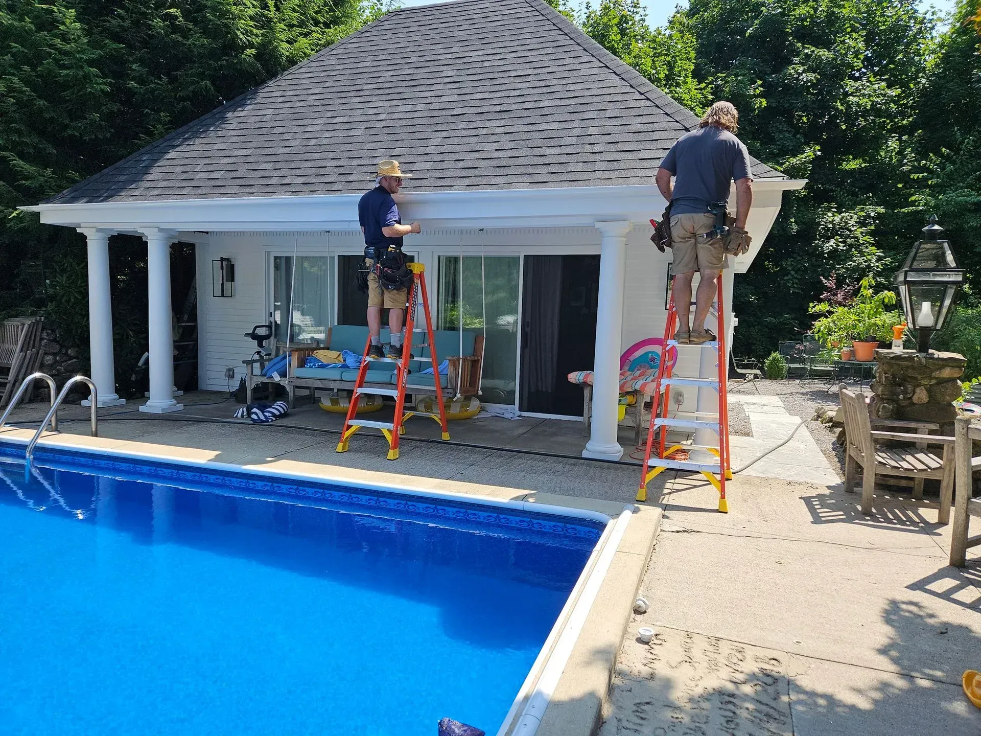 A man is standing on a ladder on the side of a brick building.