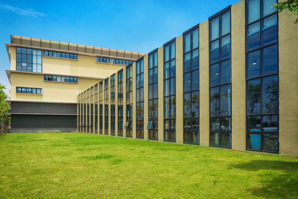 Modern building with glass windows and a green lawn under a bright sky