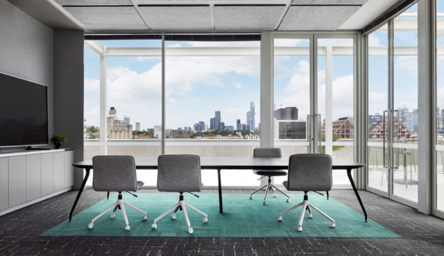 Modern conference room with large windows, teal rug, and a city skyline view