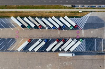 Aerial view of trucks lined up in two rows at a warehouse loading area.