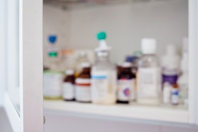 Blurred medicine bottles on a shelf in a white cabinet
