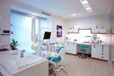 Bright modern dental office with chair, equipment, white cabinets, and teal accents