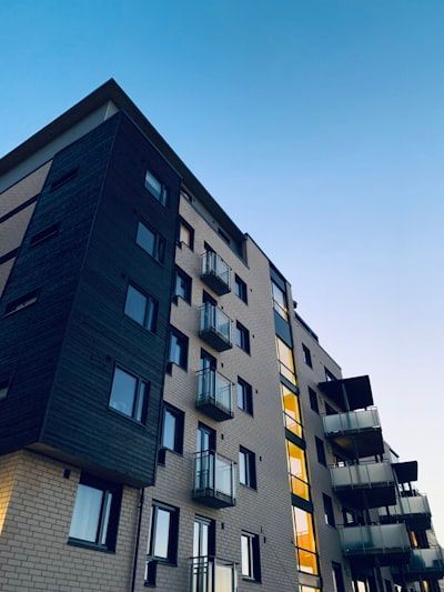 Modern apartment building with dark and light gray фасade and balconies under a blue sky