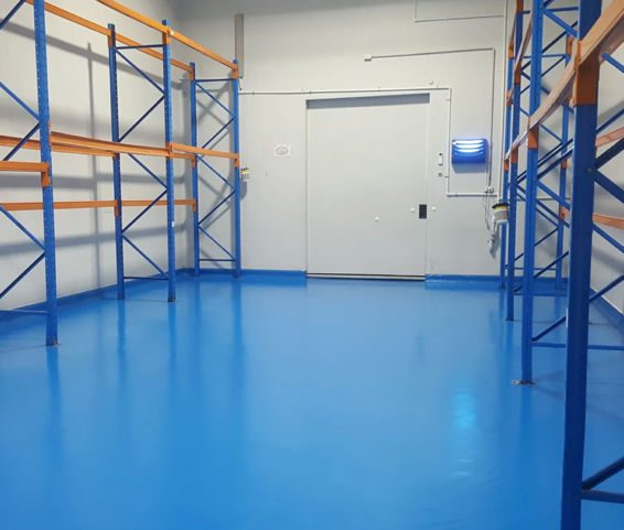 Empty blue-floored storage room with metal shelving and a closed white door
