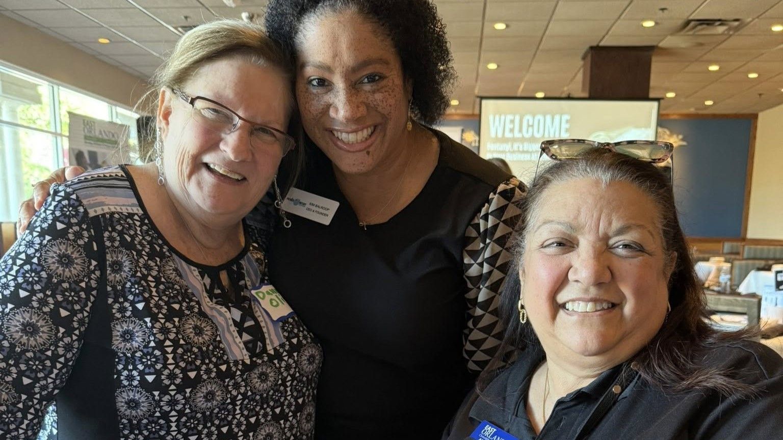 Three smiling women pose for a photo inside a restaurant; a 
