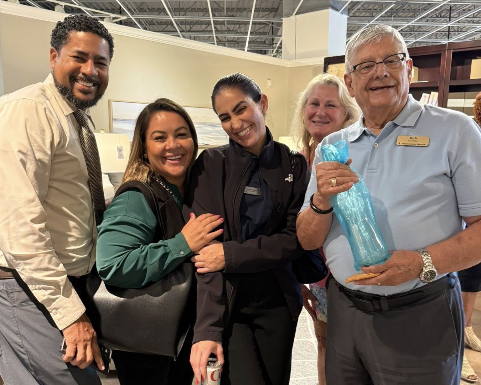 Group of people smiling, holding gifts, in what appears to be a retail store.