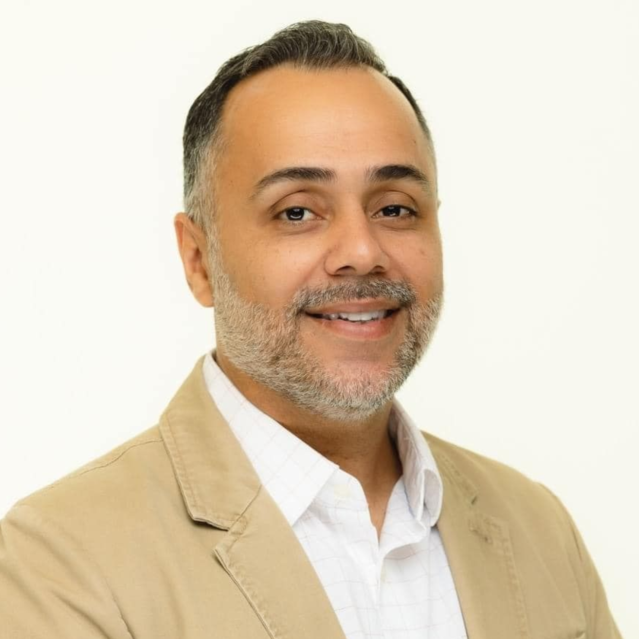 Man with a salt & pepper beard with a tan blazer and white dress shirt