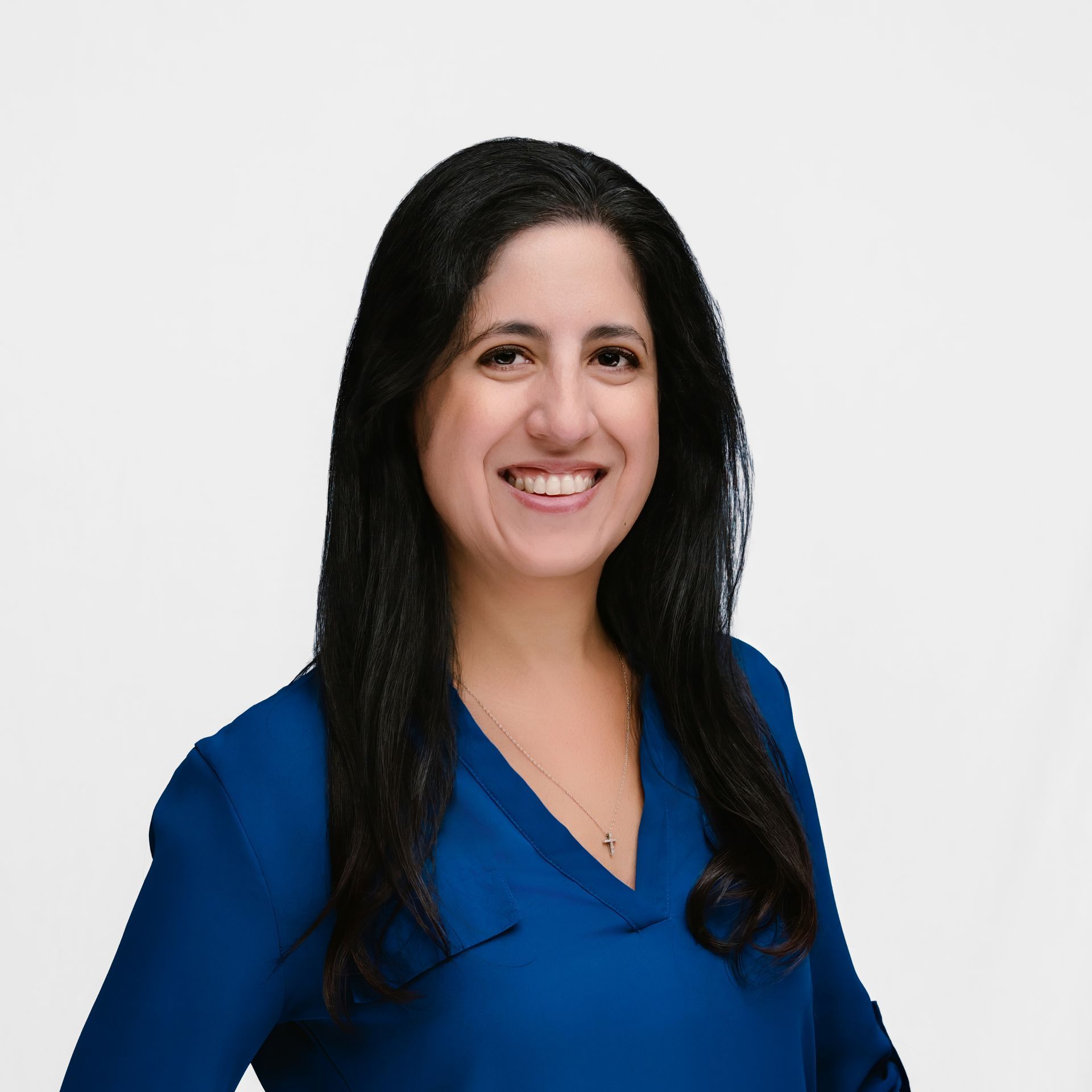 Woman with long dark hair smiles, wearing a blue shirt, against a white background.