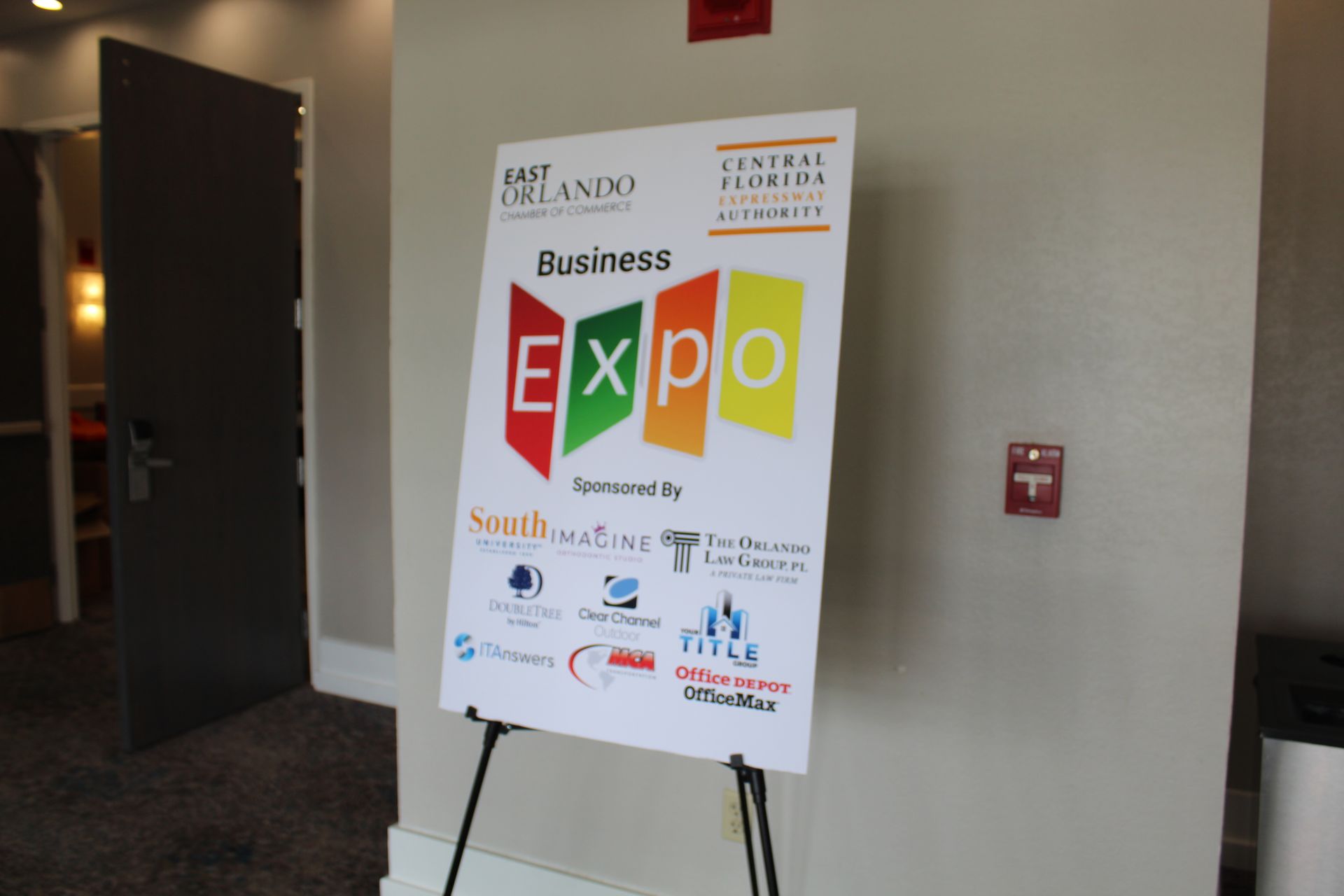 Business Expo sign with logos, easel, and open door.