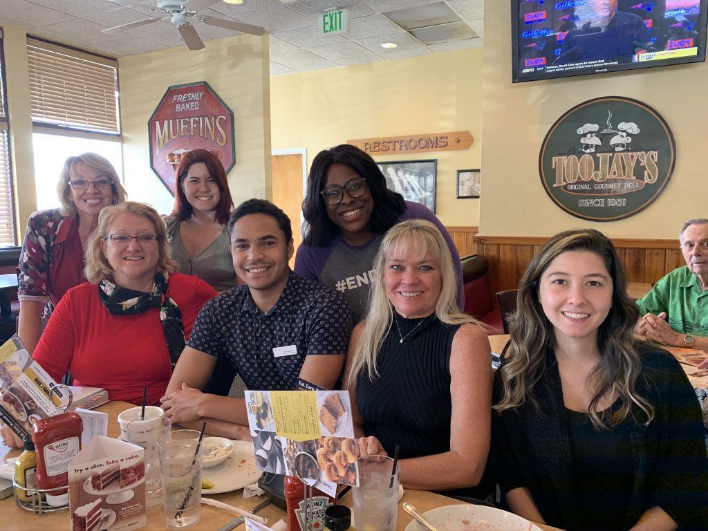 Group of people smiling at a table inside a restaurant, a Molly's Diner.