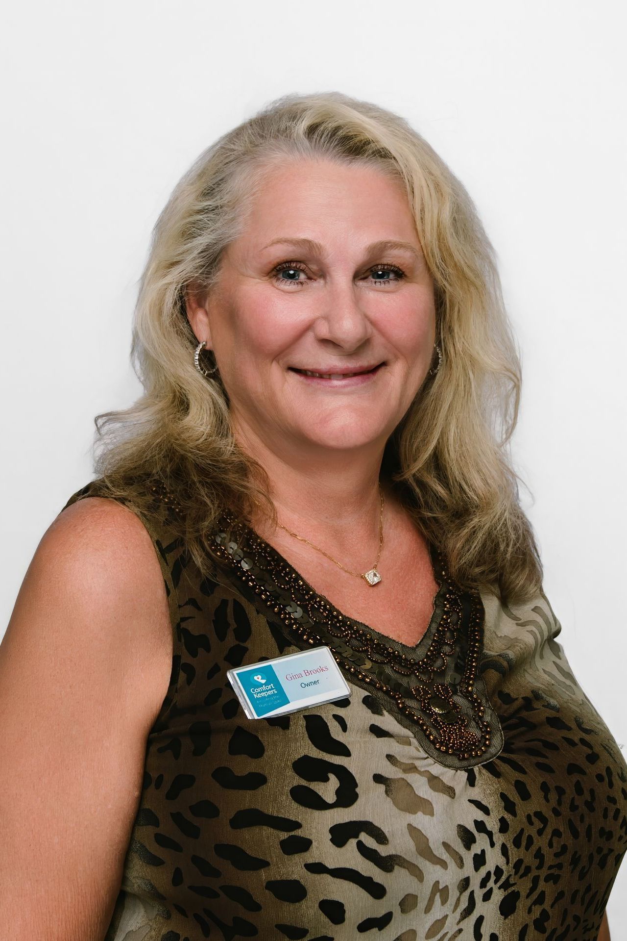 Woman with blonde hair wearing a leopard-print top, smiling and looking at the camera.