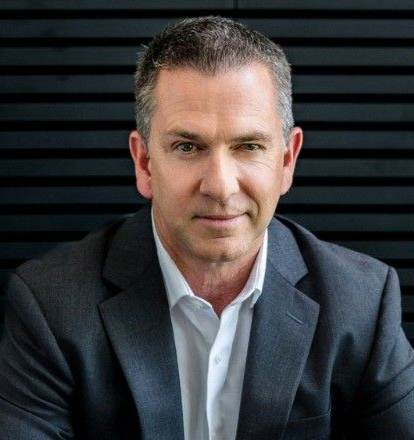 Man in a suit smiles, , business portrait on black background.
