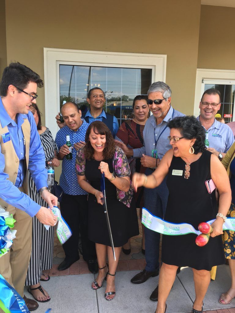 People cutting a ribbon at a business opening; group in front of a building.