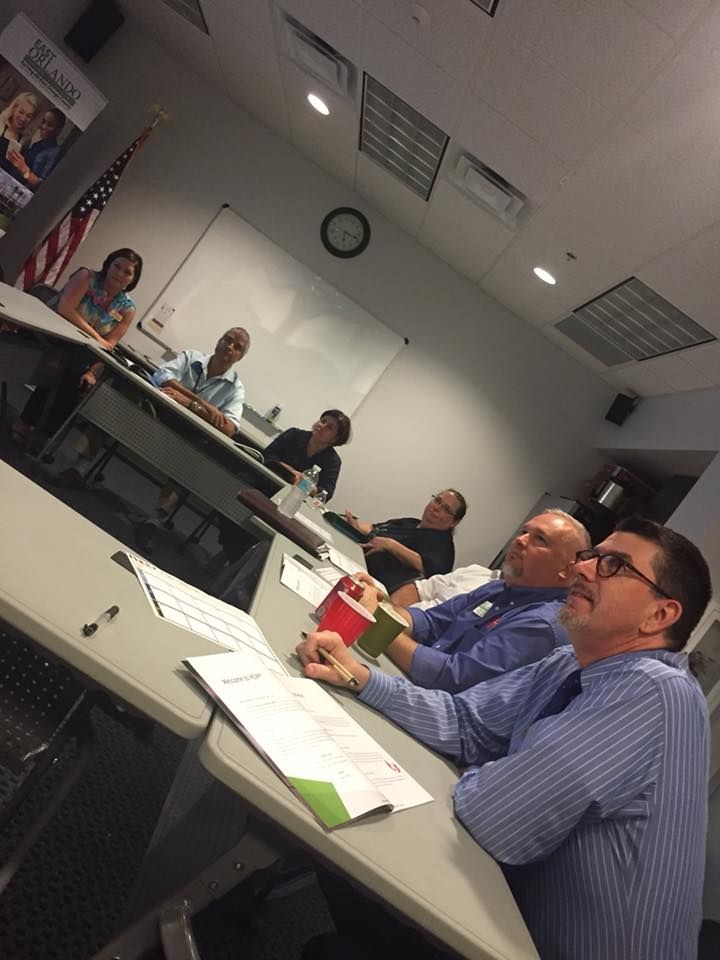People seated at a table in a meeting room with an American flag.