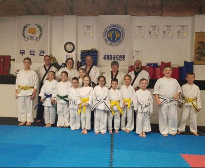 A group of kids in karate uniforms are posing for a picture