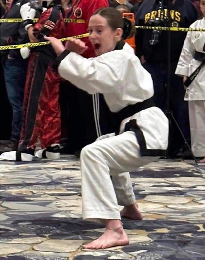 A girl in a karate uniform is squatting down