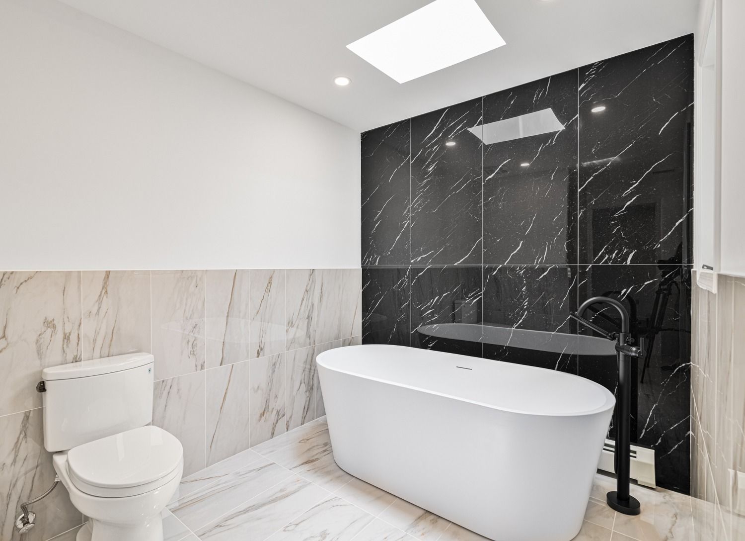 Modern bathroom with a white bathtub, black accent wall, and marble-like tile.