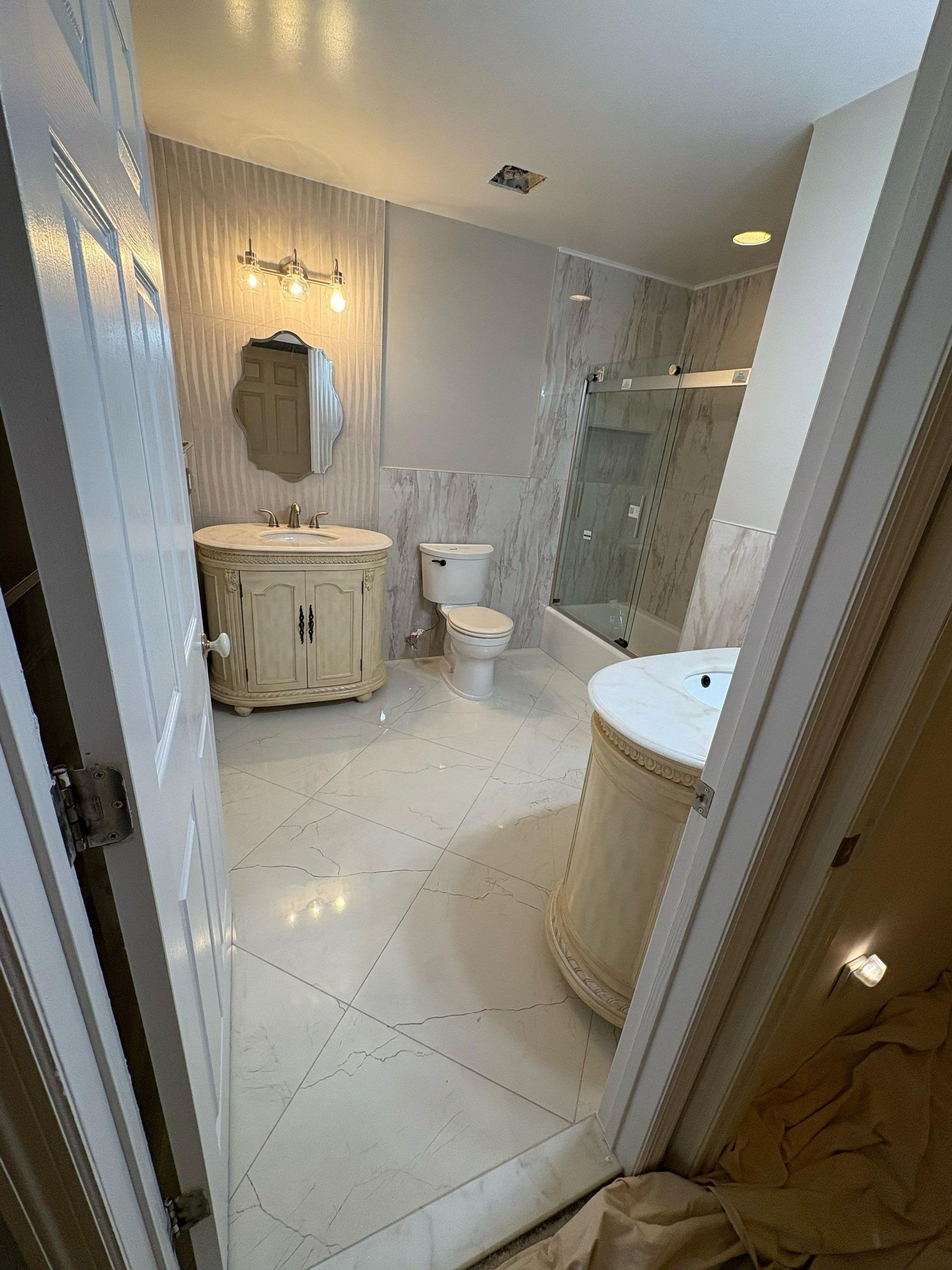 Bathroom with ornate vanity, toilet, shower, and patterned tile floor.