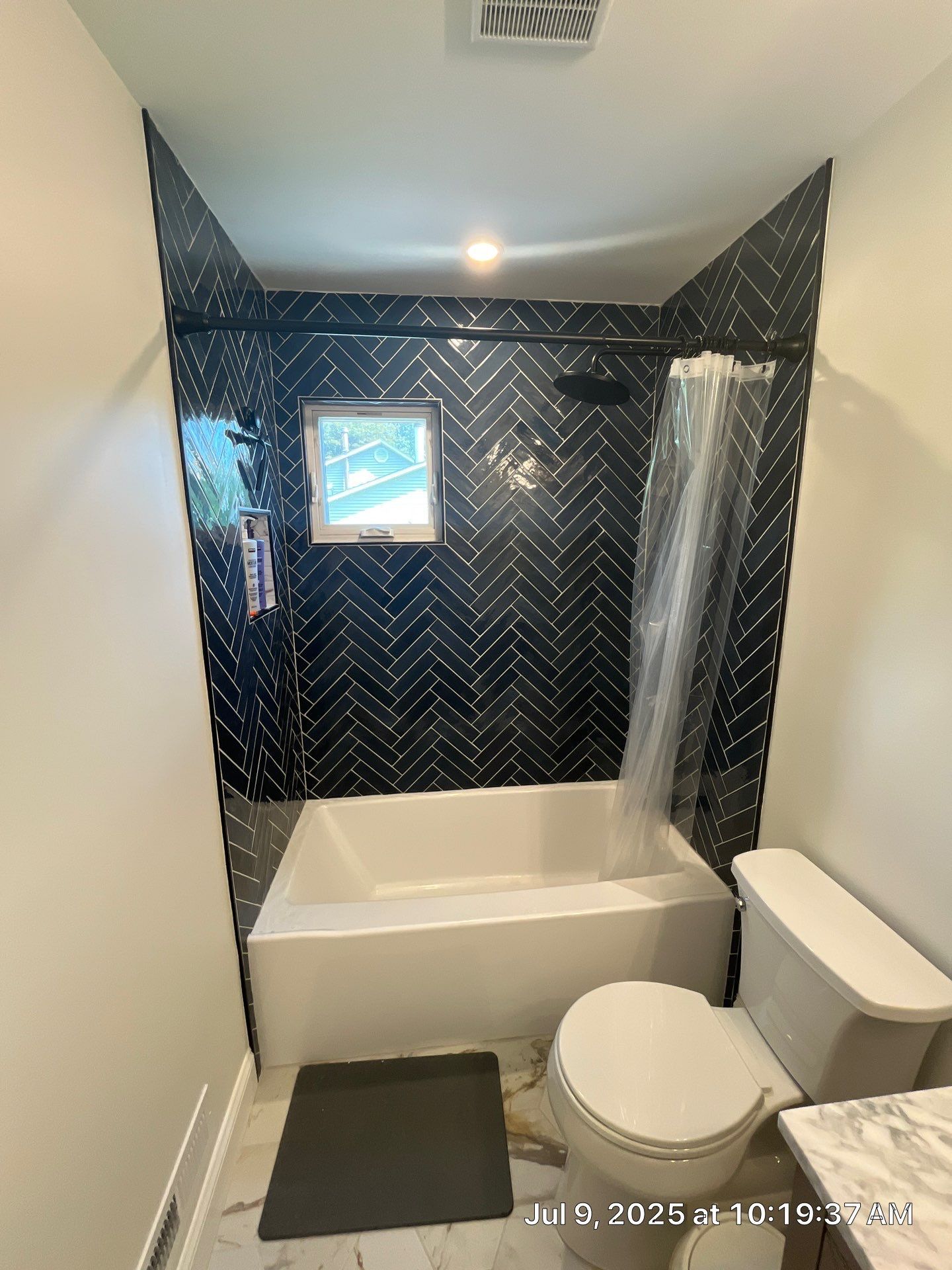 Small bathroom with a black tiled shower surround and a white tub and toilet.