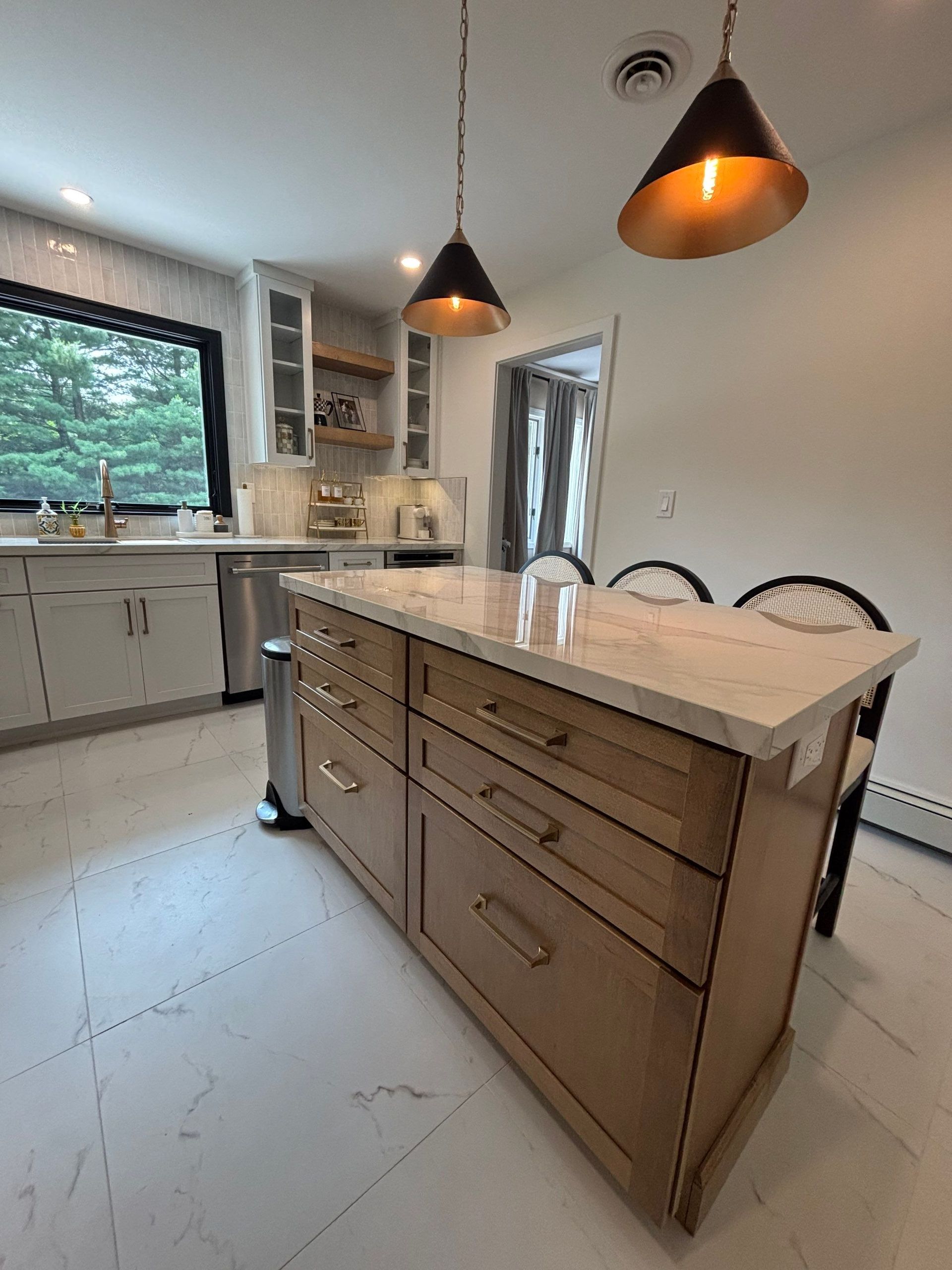 Kitchen with island, drawers, light wood cabinets, pendant lights, white countertops, and a window.