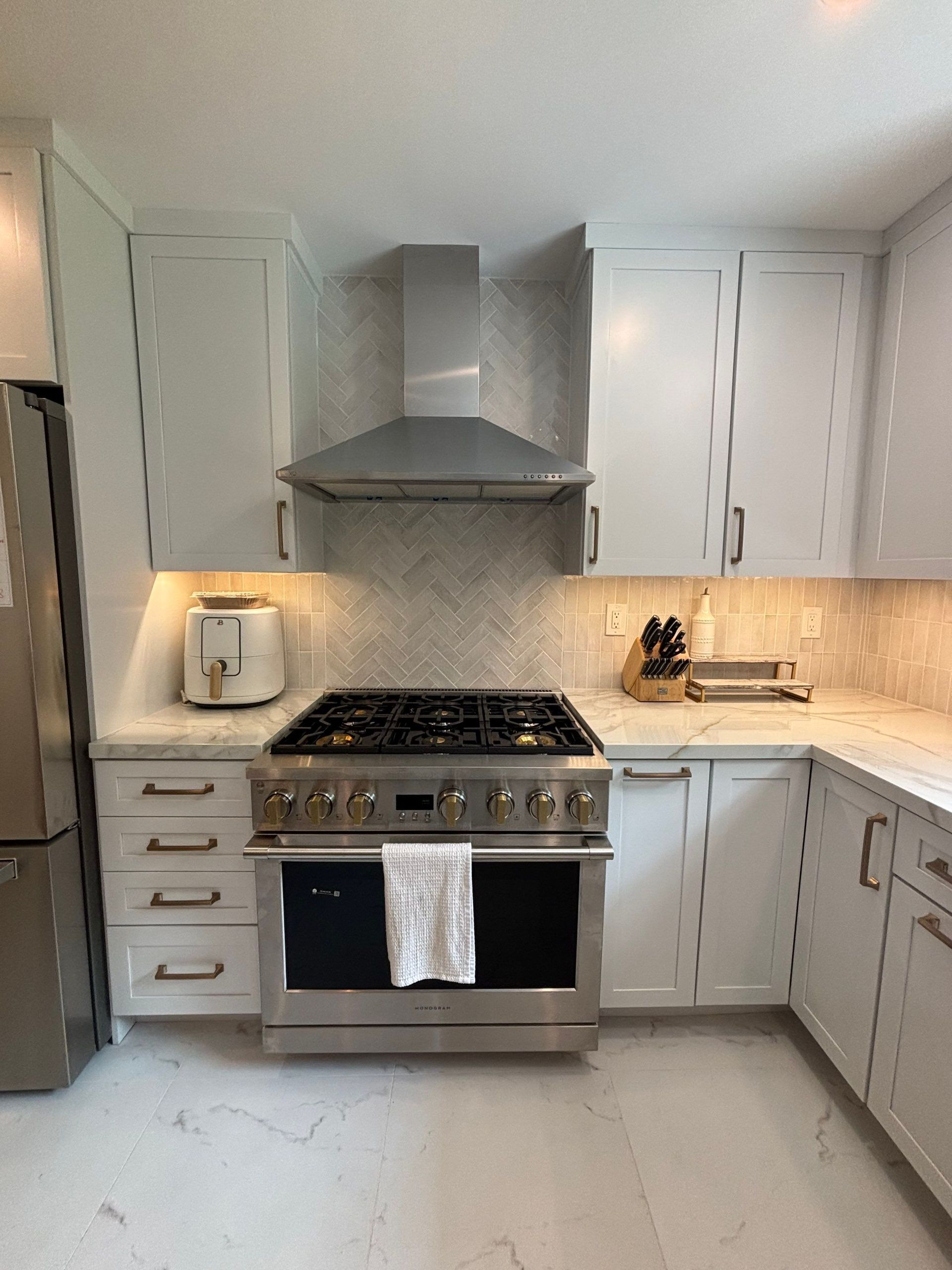 White kitchen with stainless steel range, cabinets, and hood; a toaster sits on the countertop.