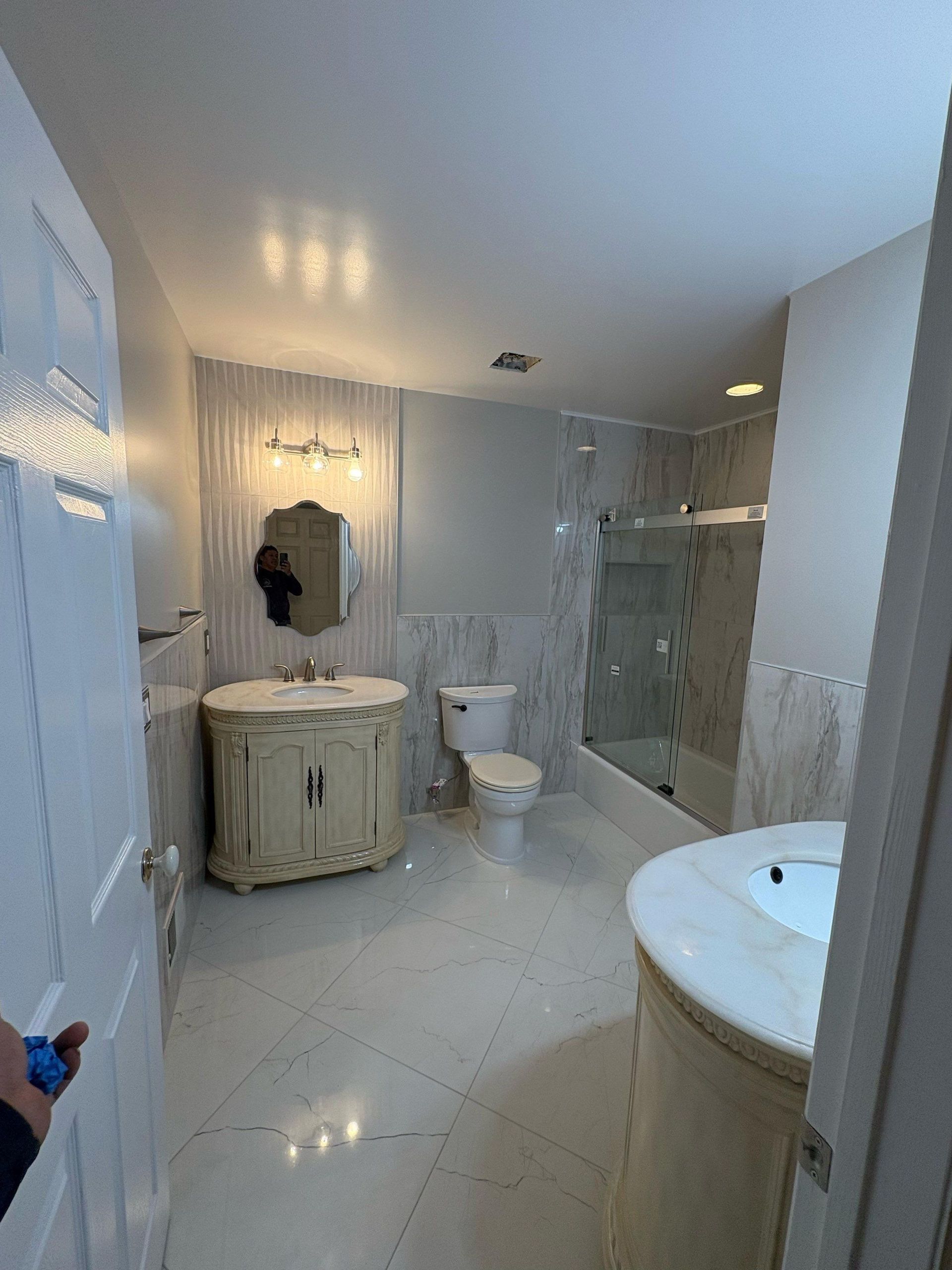 Bathroom with white tile, vanity, toilet, and shower.