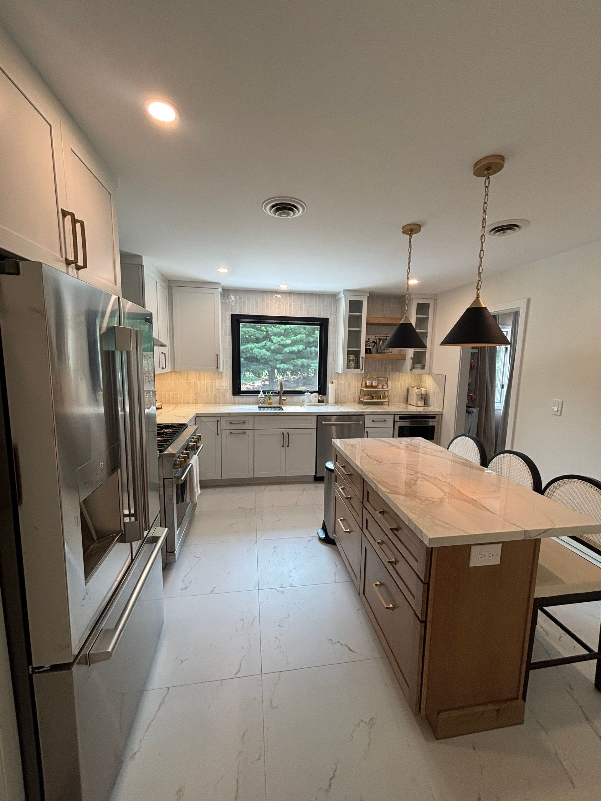 Modern kitchen with white cabinets, stainless steel appliances, and an island with seating.